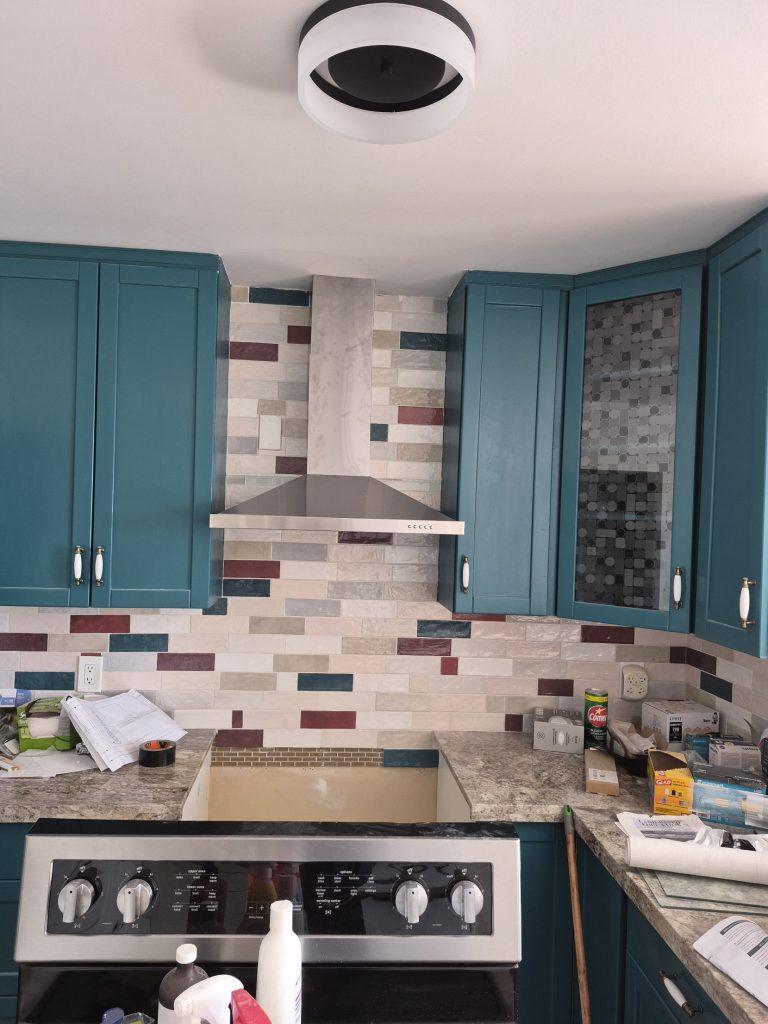 New stainless steel chimney range hood installed over an electric range in North York