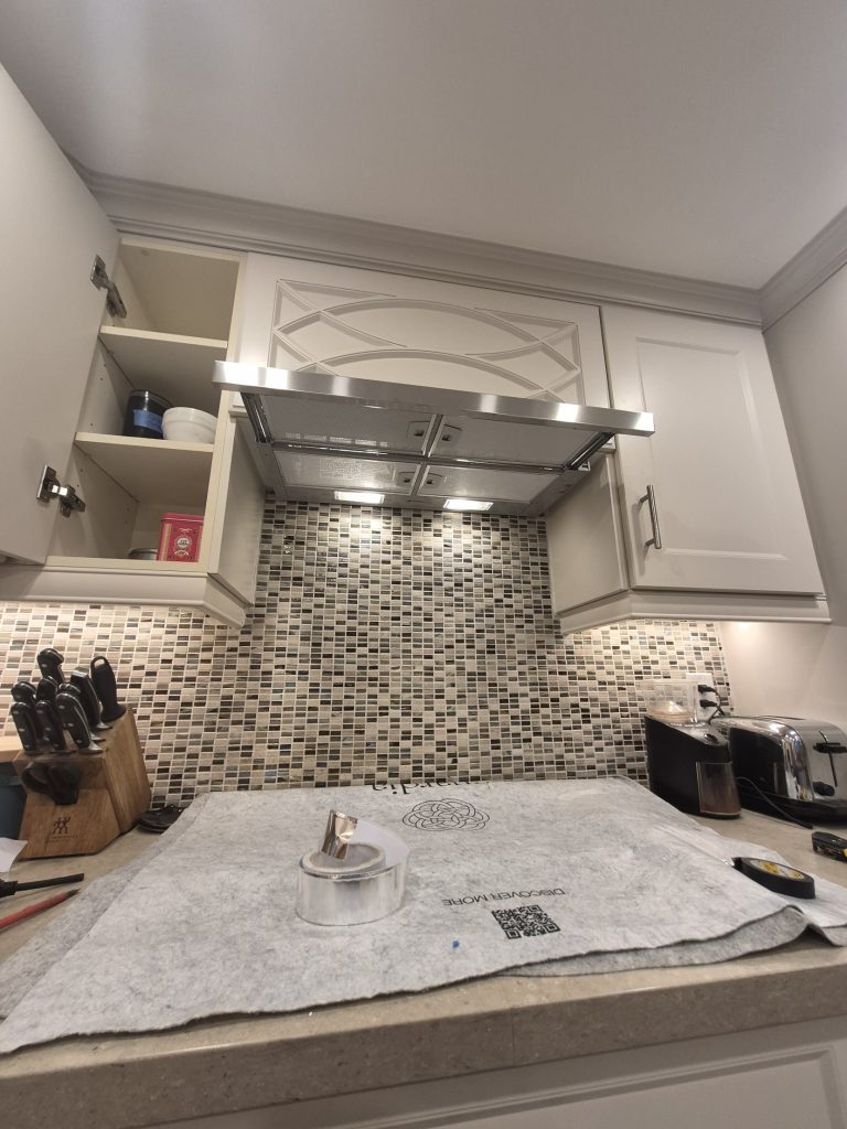 Built-in pull-out range hood installed and lit under a custom cabinet, Toronto
