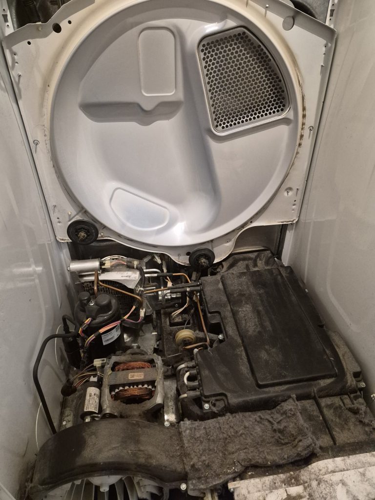 Inside a Whirlpool ventless heat pump dryer with the drum front removed, showing the compressor and lint build-up, Toronto