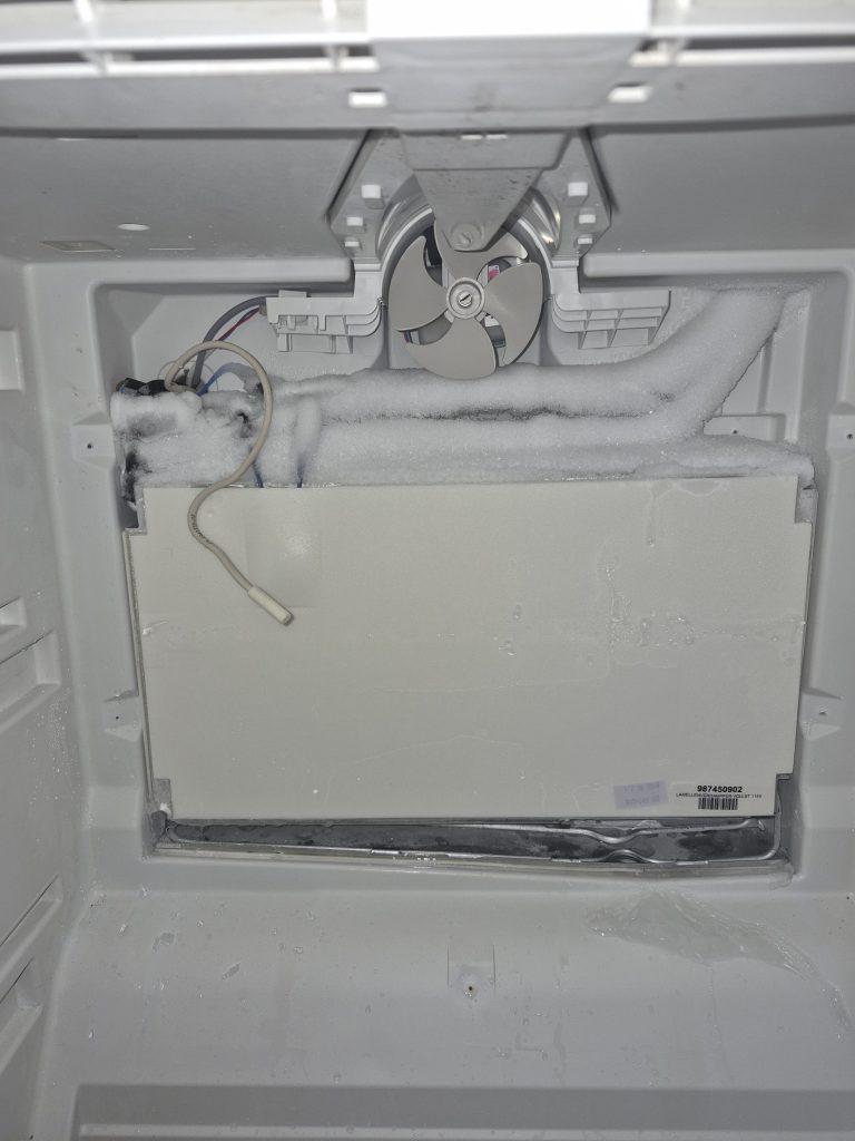 Iced-over evaporator coil behind the freezer panel of a Miele fridge, Toronto
