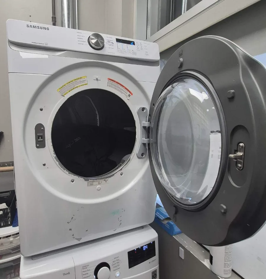 Samsung dryer stacked on an LG front-load washer in a Richmond Hill business laundry room, door open for service