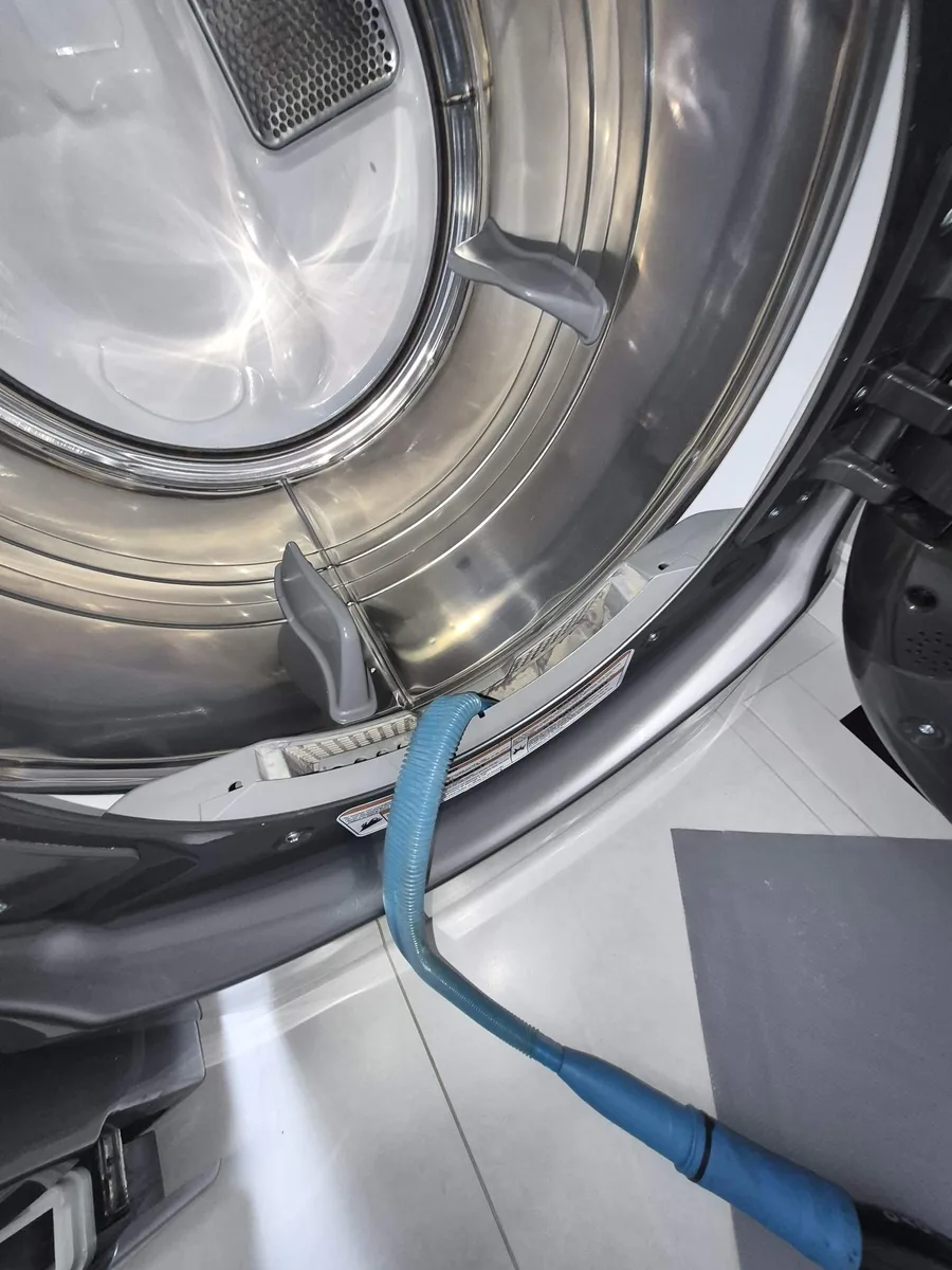 Vacuum hose clearing packed lint from a Whirlpool dryer's lint trap housing